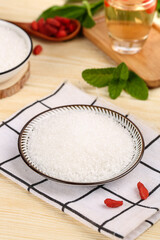 White granulated sugar in glass bowl with mint and goji berries on kitchen towel