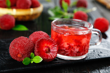 Red Fruit Tea with Fresh Strawberries and Mint Leaves in Glass Mug on Dark Slate