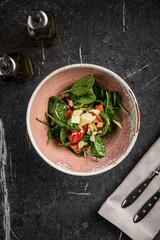 Fresh spinach salad with salmon, almonds and vegetables in ceramic bowl