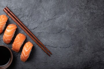 Salmon nigiri with soy sauce and chopsticks beautifully arranged on a dark slate surface, creating an elegant culinary scene