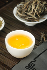 Traditional Chinese Tea Ceremony with Golden Brewed Tea and Dried Leaves on Bamboo Mat