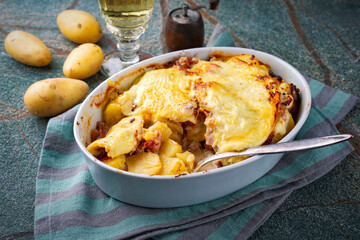 Artisan homemade oven baked tartiflette with potato and reblochon cheese served as close-up in casserole dish