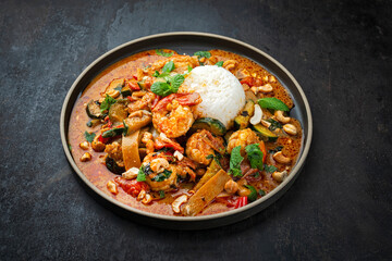 Traditional Thai red curry with king prawns and vegetable - kaeng phet as top view in a bowl with jasmin rice