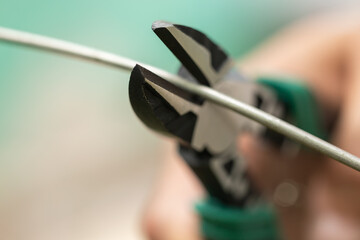 Cutting pliers and cable. A cutter is cutting electrical wire or cable. Cutting wires with clippers. Metal nippers