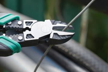 Hands hold nippers, cutting through wires while preparing electrical connections.