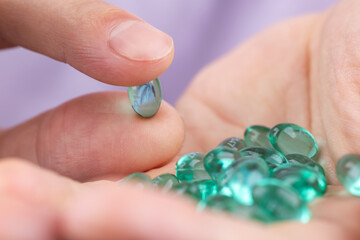 Man's hand holding blue gel capsule Close up