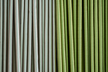 Close up view of fabric curtains in two contrasting colors, silver and green, with soft folds and texture, representing home decor, interior design, textile industry, and modern style.