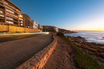 A view of a coastal road in Concon, with the ocean and rocks illuminated by the last light of day.