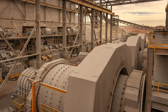 A close up of ball mills in a copper processing plant in Arequipa, Peru, with conveyors and other industrial equipment.