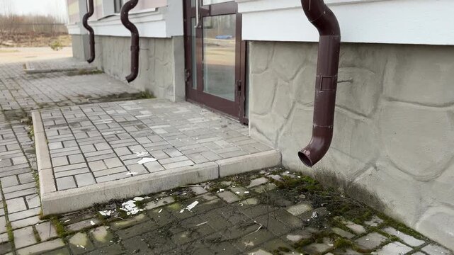 Gutter downspout, flexible rain gutter extension next to house wall 
