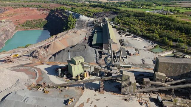 Aerial drone view of huge quarry mining operational facility, extracting rare earth minerals, heavy plant machinery and industrial conveyor belts in Coalville England UK sunny 