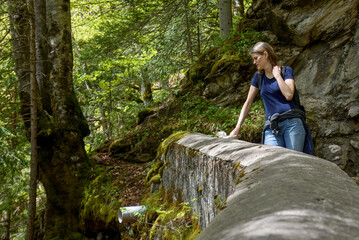 Hiker taking a pause and leaning on a stone wall to breathe and contemplate the forest in a peaceful natural setting