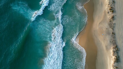 Aerial view of ocean waves crashing onto a sandy beach, capturing the dynamic beauty of nature.