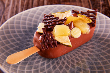  Schokoliertes Stieleis liegend mit Birne und Schokoladendeko, Eis am Stiel, Schokoladeneis,...