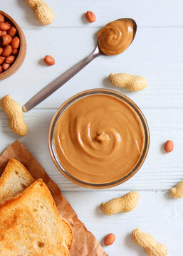creamy peanut butter and peanuts beans on wooden background top view. Vertical photo format