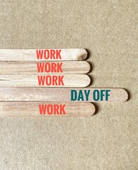 A group of wooden sticks has the word Work repeated four times and the other one stick saying Day...
