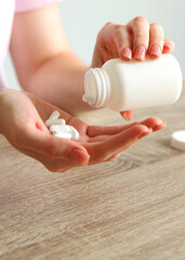 Young girl in a good mood takes pills at home. Vertical photo format