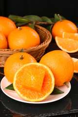 Fresh Orange Citrus Fruits on White Plate and Wicker Basket with Green Leaves