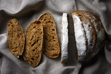 Appetizing rye sourdough bread slices on a rustic linen towel. Artisan farmhouse-style loaf close up