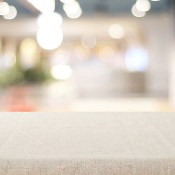 Empty table with linen tablecloth over blurred abstract with bokeh background banner, food and product display montage template, backdrop, wallpaper