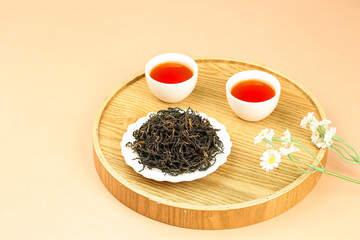 Black tea ceremony with organic loose tea leaves and cups on wooden serving tray