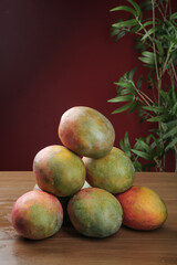 Fresh Ripe Mangoes on Wooden Table with Green Plant Background