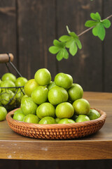 Fresh Green Plums in Wicker Basket on Rustic Wooden Table with Natural Background