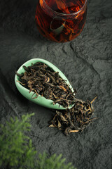 Fototapeta premium Organic Mountain Tea Leaves with Brewed Cup - Premium Plantation Tea on Dark Slate Background