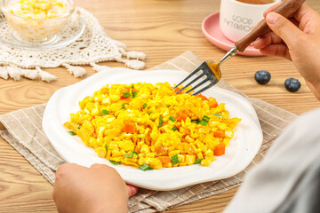 Golden scrambled eggs with fresh corn kernels and vegetables on white plate, healthy breakfast main dish