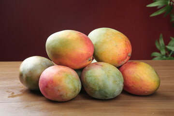 Fresh Ripe Mangoes on Wooden Table with Tropical Leaves Background