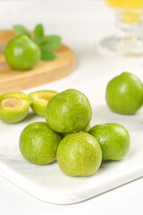 Fresh Green Sichuan Plums with Water Droplets on White Marble Board