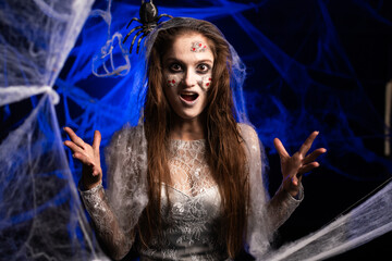 Angry aggressive creepy woman with horrible scary Halloween zombie makeup in white dress standing...