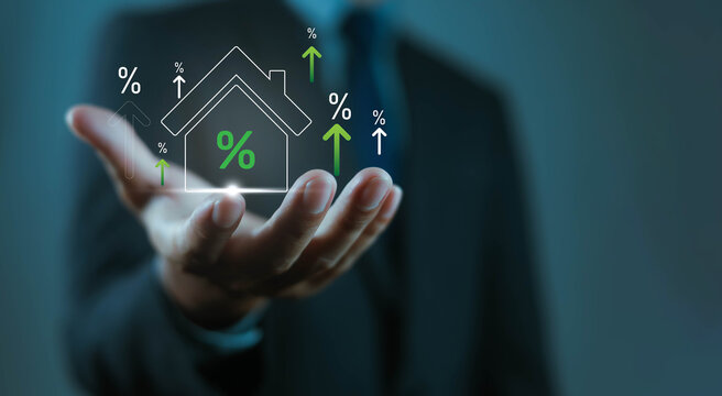 Businessman holding house icon with rising percentage signs, symbolizing real estate growth, property investment, mortgage rates, housing market, financial success, home value, economic development.