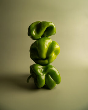 Naklejki Artistic abstract still life of green bell peppers with surreal organic shapes, sculptural vegetable stack, creative minimal food photography, concept, healthy eating, balancing structure