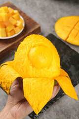 Fresh Ripe Golden Mango in Hand with Sliced Fruit Pieces on Cutting Board - Tropical Summer Produce