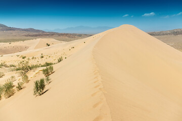 Footprints are visible on the side of a sand dune rising in the desert landscape of Altyn Emel National Park in Kazakhstan