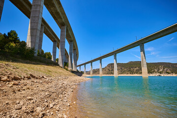 Tranquil scenery under a bridge over a reservoir with crystal clear turquoise water