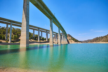 Tranquil scenery under a bridge over a reservoir with crystal clear turquoise water