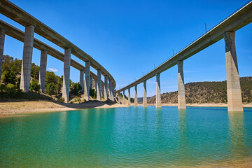 Tranquil scenery under a bridge over a reservoir with crystal clear turquoise water
