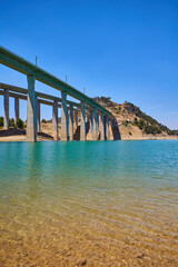 Tranquil scenery under a bridge over a reservoir with crystal clear turquoise water