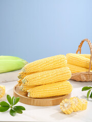 Fresh Sweet Yellow Corn Cobs on Wooden Display Board with Wicker Basket