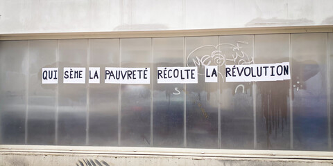 French protest poster stuck on a wall by left wing feminists saying "he who sows poverty reaps revolution"