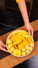Golden fried chicken with corn on plate held by hands on wooden board kitchen scene