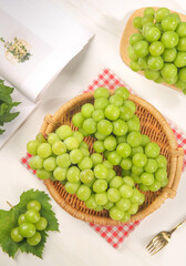 Fresh Green Grapes in Rustic Wicker Basket on White Wood Table with Natural Sunlight