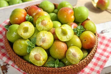 Fresh Sichuan Red Plums in Wicker Basket with Mint Garnish