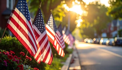 A row of American flags lines a street, bathed in golden sunlight. The flags' colors pop against the warm glow, with a blurry background of homes