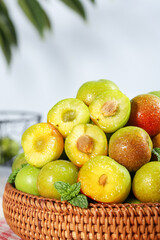 Fresh Ripe Plums in Wicker Basket with Water Droplets and Mint Garnish