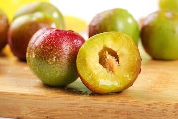 Fresh Ripe Plums Cut in Half on Wooden Cutting Board Showing Yellow Flesh and Pit