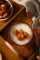 Asian Rice Porridge with Glazed Nuts and Star Anise on Bamboo Tray - Traditional Comfort Food