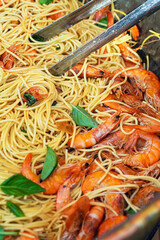 Pasta with Shrimps. Delicious spaghetti with shrimp and basil, freshly cooked and served in a rustic pan. Concept of shrimp pasta, seafood cuisine and Mediterranean flavor